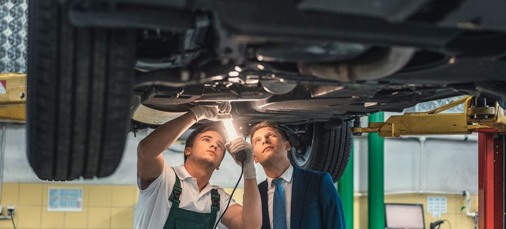 Cliente con un mecánico revisando el coche de un taller